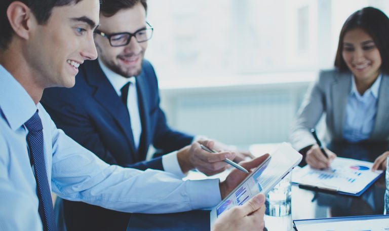 Image of businessman pointing at document in touchpad while interacting with his partner at meeting